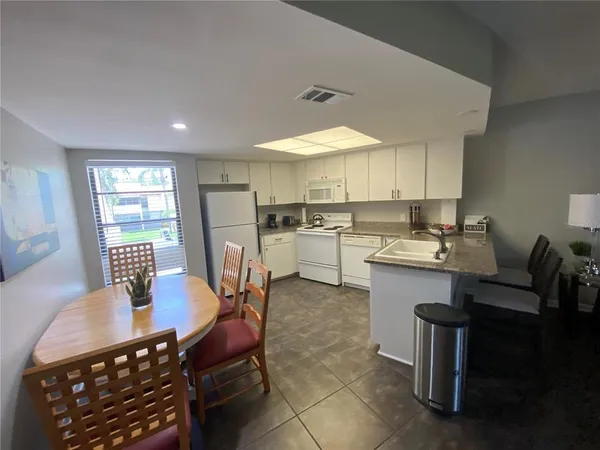 a kitchen with a dining table chairs and refrigerator