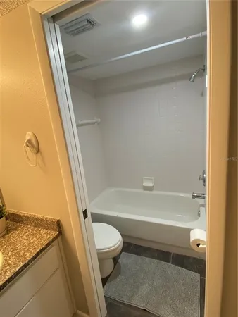 a bathroom with a granite countertop bathtub shower and toilet
