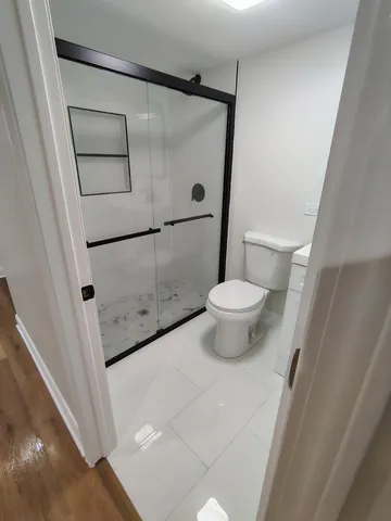 a bathroom with a sink a toilet a mirror and shower