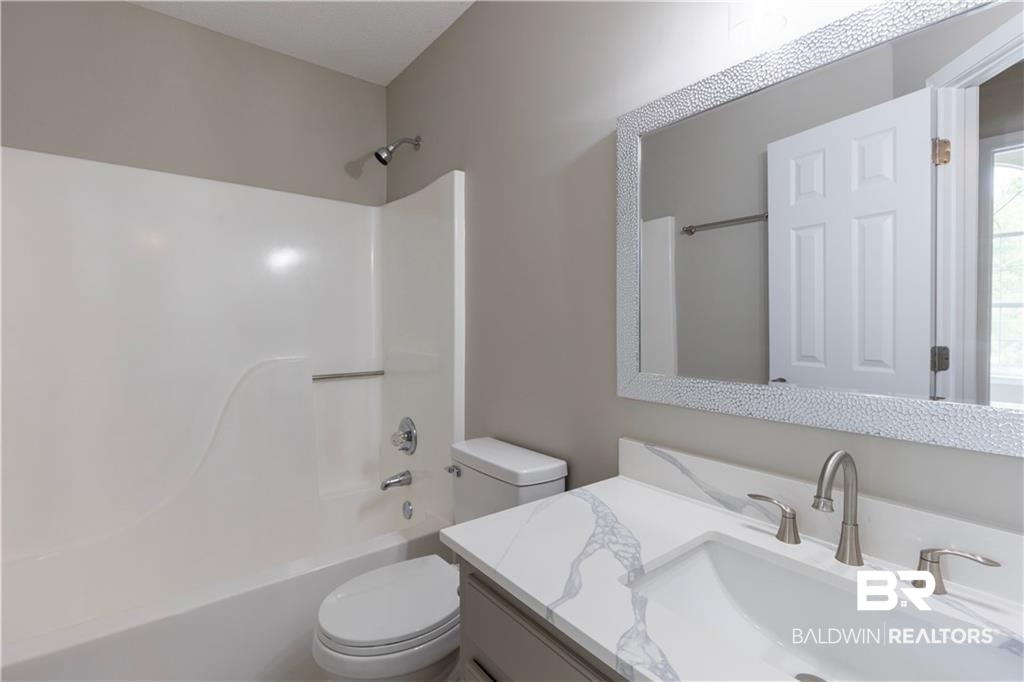 101 Lawson Road Daphne, AL 36526 - Photo 15 of 20 Bathroom featuring a white integrated tub/shower unit with chrome fixtures, a modern vanity with a white countertop and integrated sink, brushed nickel faucet, and a large framed mirror