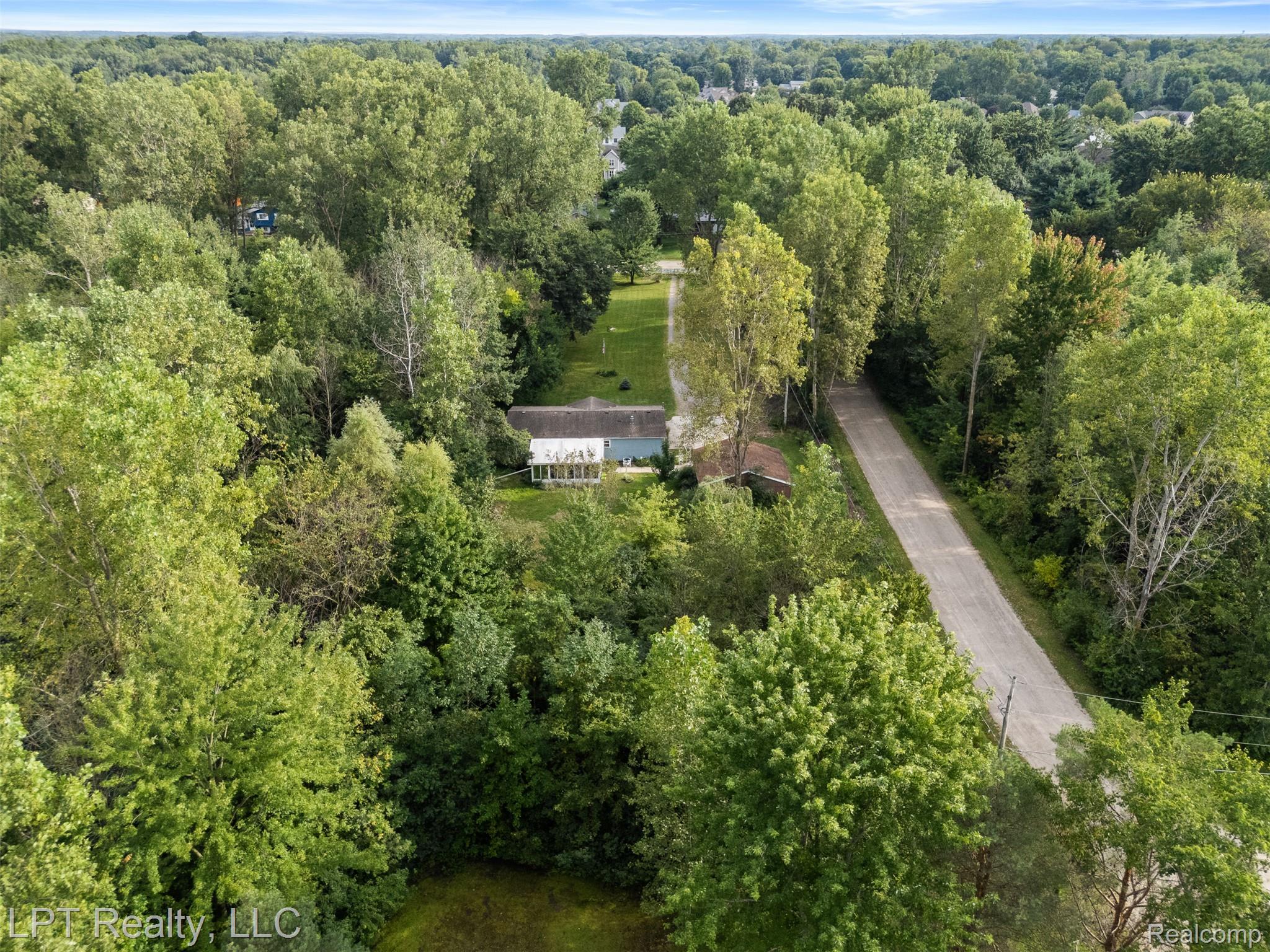 6271 East Potter Road Davison, MI 48423 - Photo 40 of 41 Aerial view of property and surrounding area with a heavily wooded area