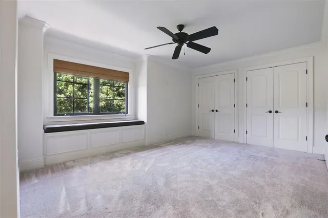 an empty room with windows and ceiling fan
