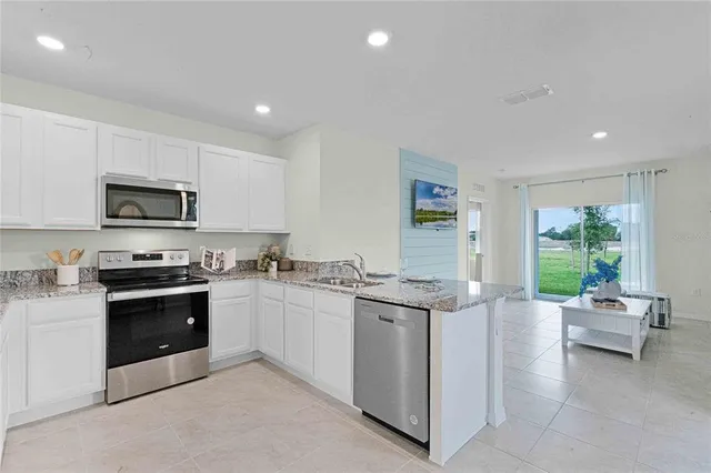 a kitchen with stainless steel appliances granite countertop a stove top oven a sink dishwasher and white cabinets