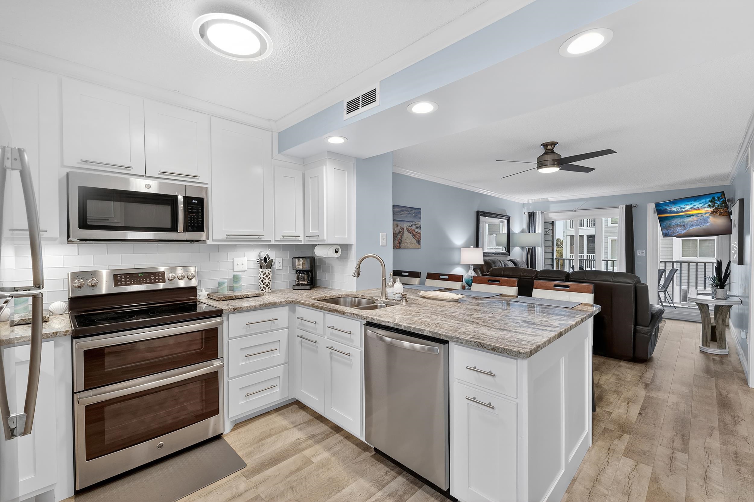 9581 Shore Drive, Unit 229 Myrtle Beach, SC 29572 - Photo 10 of 39 Kitchen with stainless steel appliances, ornamental molding, light stone countertops, a peninsula, and white cabinets
