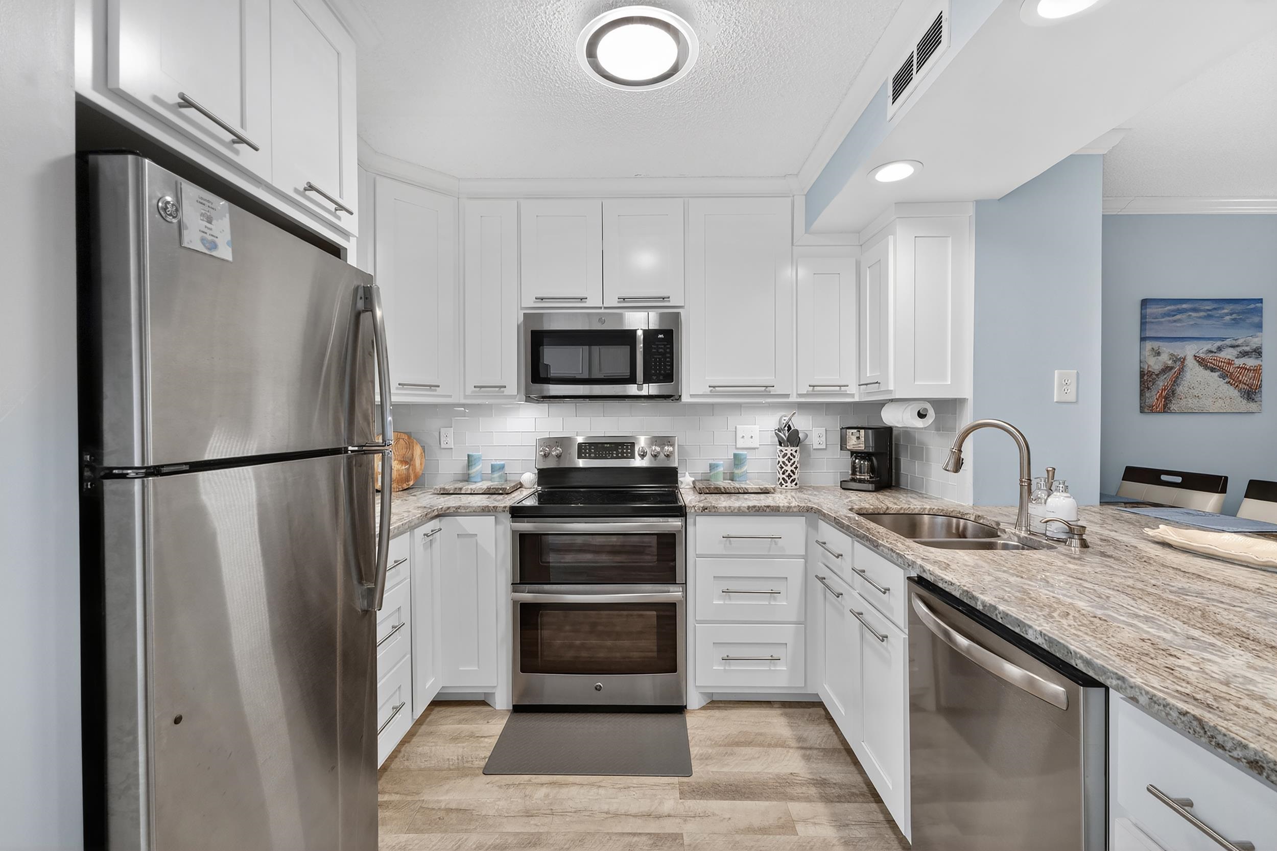 9581 Shore Drive, Unit 229 Myrtle Beach, SC 29572 - Photo 11 of 39 Kitchen with appliances with stainless steel finishes, white cabinets, light stone countertops, light wood-style floors, and tasteful backsplash