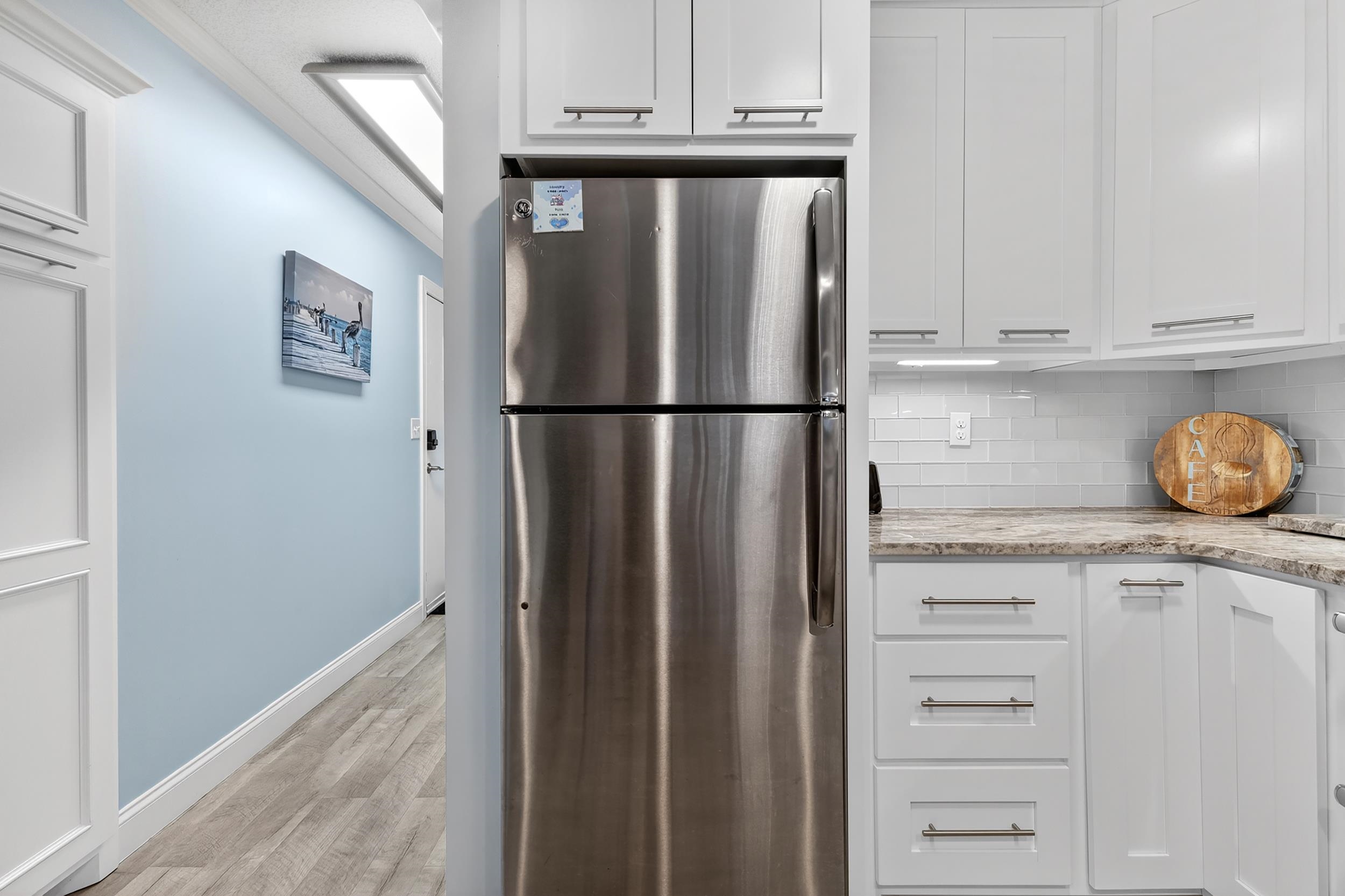 9581 Shore Drive, Unit 229 Myrtle Beach, SC 29572 - Photo 12 of 39 Kitchen with freestanding refrigerator, white cabinetry, light stone countertops, and light wood-style flooring