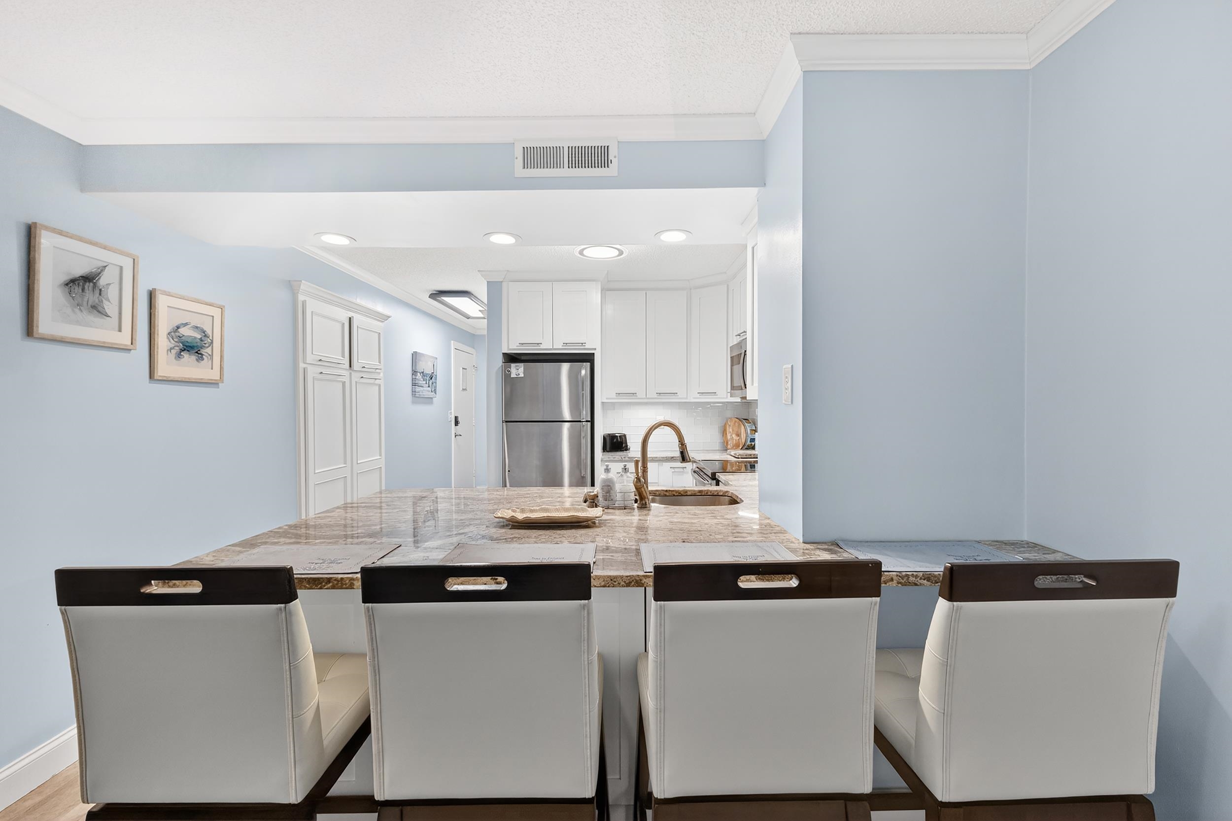 9581 Shore Drive, Unit 229 Myrtle Beach, SC 29572 - Photo 15 of 39 Kitchen featuring a kitchen breakfast bar, white cabinets, freestanding refrigerator, ornamental molding, and a peninsula