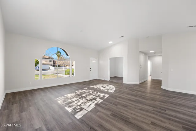 a view of empty room with wooden floor and window