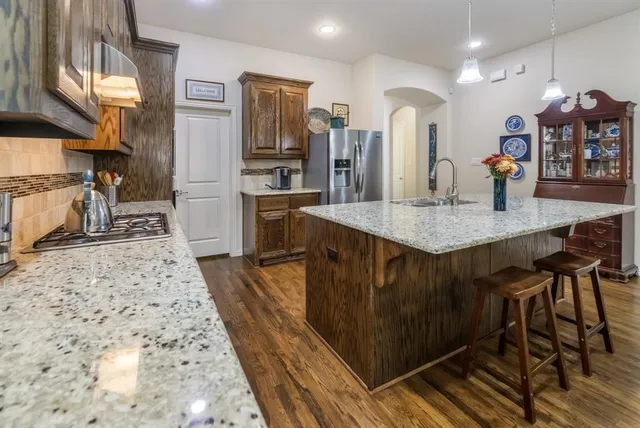 a kitchen with stainless steel appliances kitchen island granite countertop a table chairs in it and wooden floors
