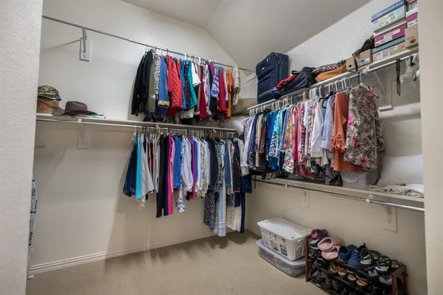 a view of walk in closet with clothes and shoes