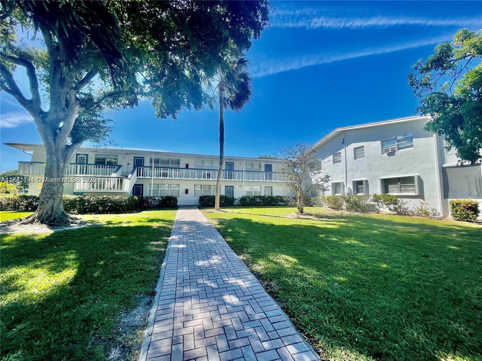 a view of a patio with couches table and chairs under an umbrella