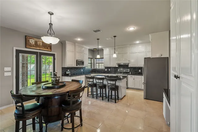 a kitchen with a dining table chairs stainless steel appliances and cabinets