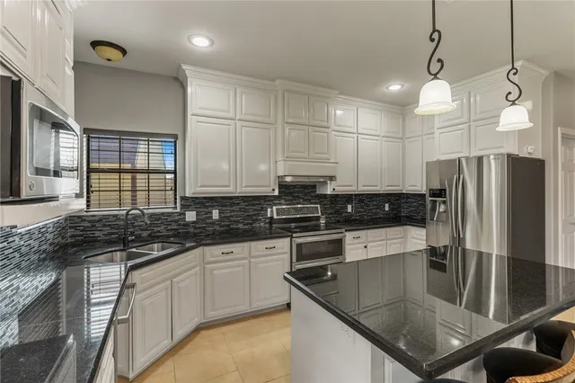 a kitchen with stainless steel appliances granite countertop a sink a stove and refrigerator