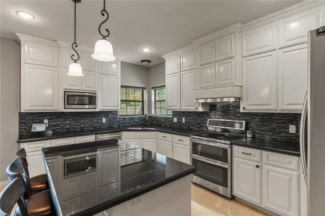 a kitchen with stainless steel appliances a stove a sink and white cabinets