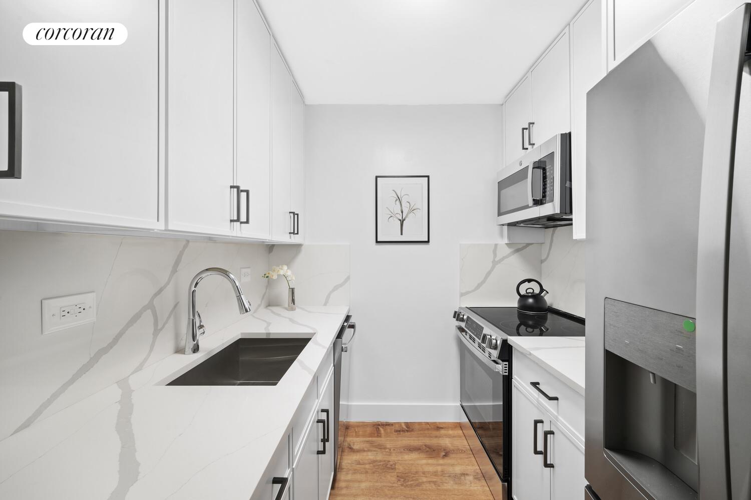 636 Washington Street, Unit 3B Manhattan, NY 10014 - Photo 4 of 9 a kitchen with white cabinets sink and stainless steel appliances