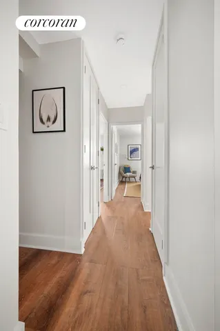 a view of a hallway with wooden floor and a bathroom