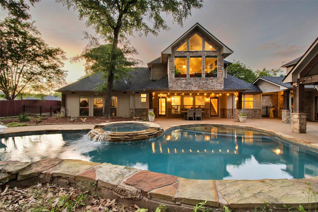 Backyard oasis featuring a swimming pool with integrated spa, stone retaining wall, and extended patio
