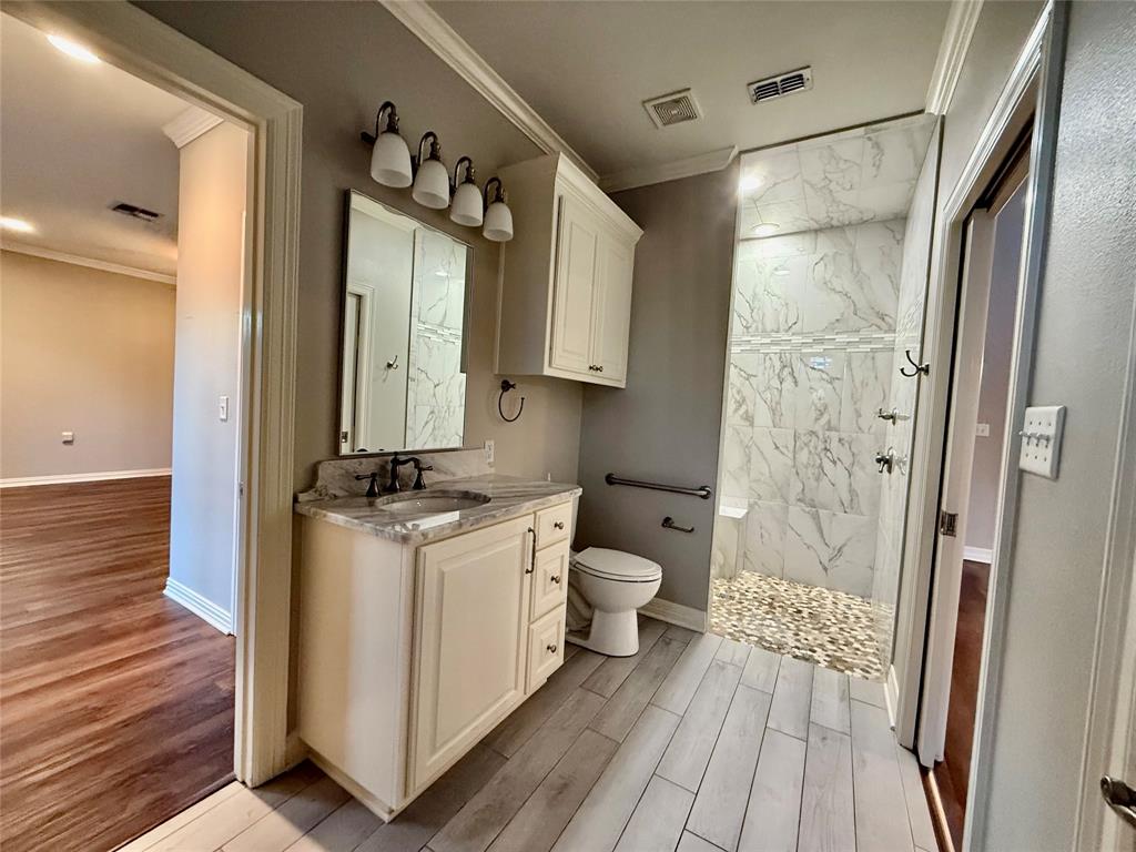 3815 Holly Ridge Drive, Unit GUEST Longview, TX 75605 - Photo 17 of 31 Bathroom with ornamental molding, light wood-style flooring, vanity, and a marble finish shower