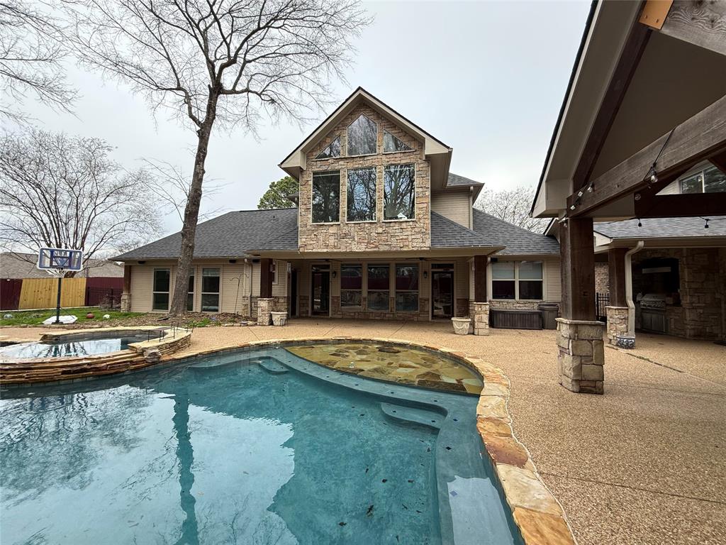 3815 Holly Ridge Drive, Unit GUEST Longview, TX 75605 - Photo 2 of 31 Rear view of property with stone siding, roof with shingles, a patio, and a pool with connected hot tub