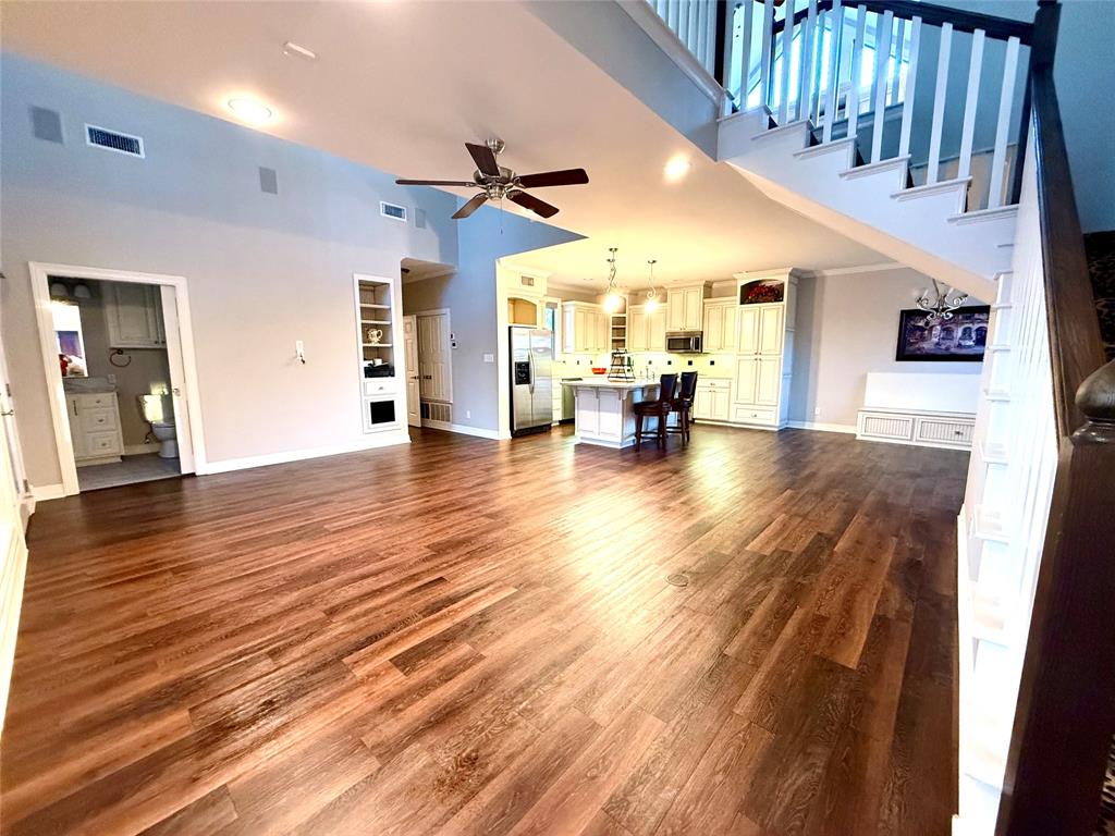 3815 Holly Ridge Drive, Unit GUEST Longview, TX 75605 - Photo 3 of 31 Unfurnished living room featuring ceiling fan, built in shelves, dark wood finished floors, and a high ceiling
