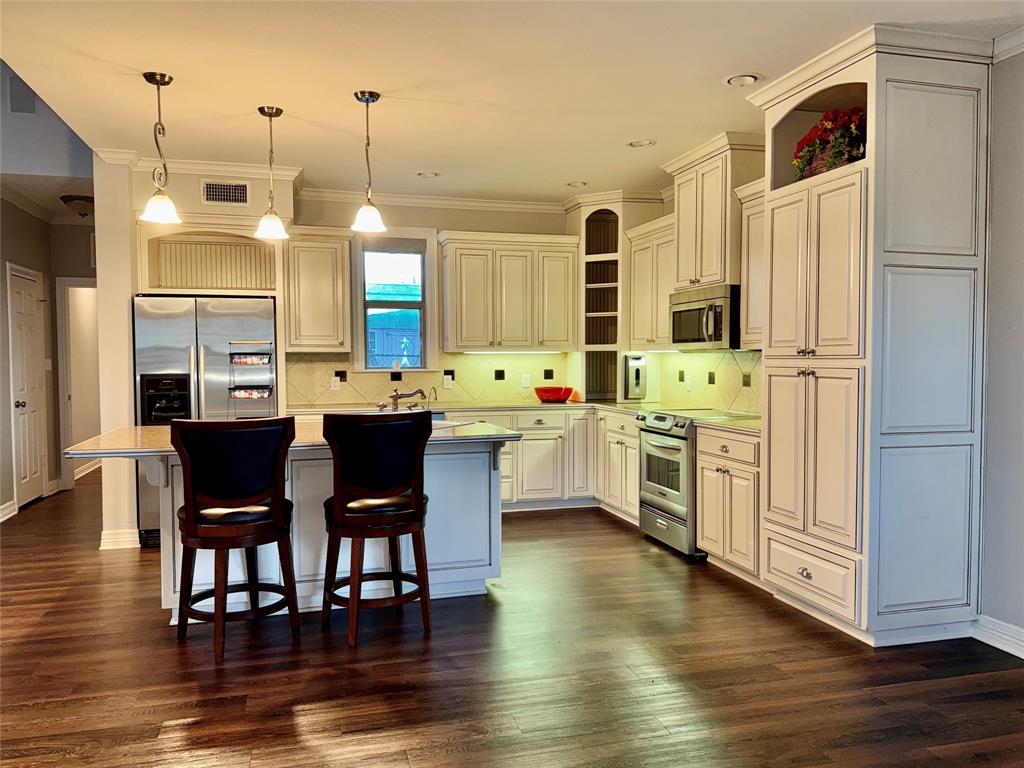 3815 Holly Ridge Drive, Unit GUEST Longview, TX 75605 - Photo 5 of 31 Kitchen with a breakfast bar area, ornamental molding, stainless steel appliances, a center island, and pendant lighting