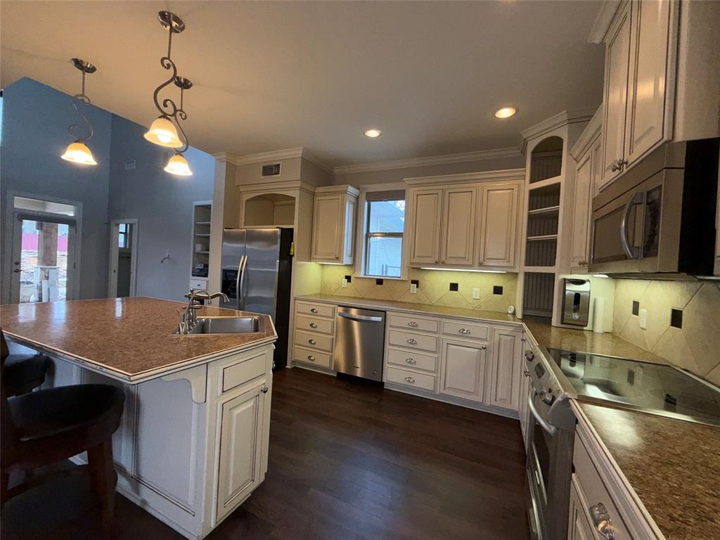 3815 Holly Ridge Drive, Unit GUEST Longview, TX 75605 - Photo 7 of 31 Kitchen featuring stainless steel appliances, a kitchen breakfast bar, a kitchen island with sink, backsplash, and dark wood-type flooring