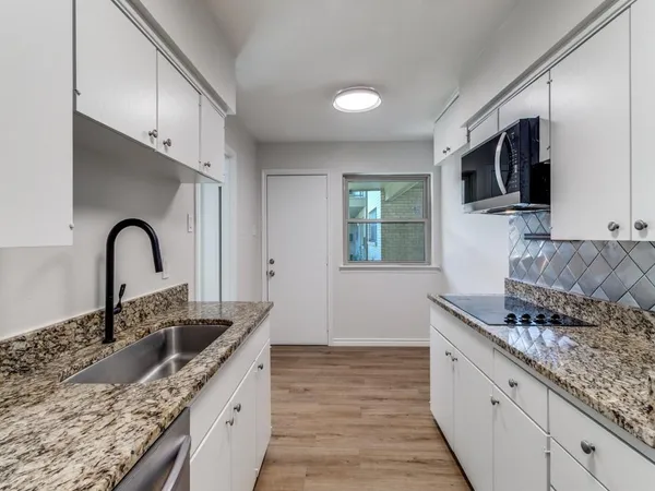 a kitchen with granite countertop a sink and a stove top oven