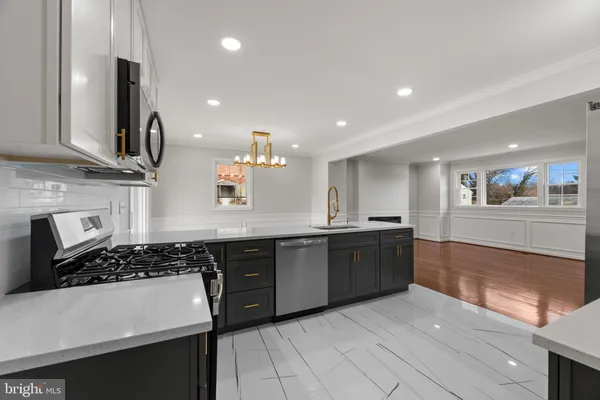 a large kitchen with stainless steel appliances a sink dishwasher a refrigerator and a stove with wooden floor