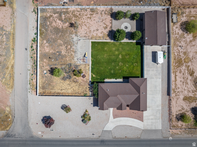 4635 East Sunny Acres Lane Moab, UT 84532 - Photo 14 of 56 Expansive property featuring a brown-roofed residence, a separate accessory structure, a large manicured lawn, a concrete driveway, and a decorative gravel fire pit area