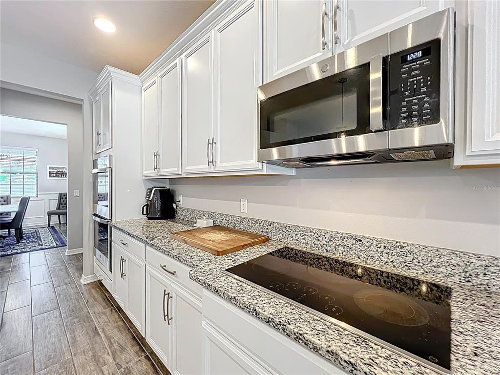 2676 Estuary Loop Oviedo, FL 32765 - Photo 20 of 92 a kitchen with stainless steel appliances kitchen island granite countertop a stove a sink and a microwave