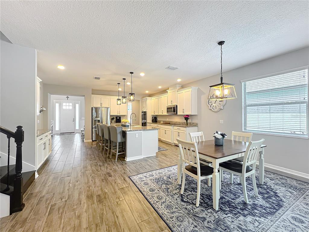 2676 Estuary Loop Oviedo, FL 32765 - Photo 24 of 92 a dining room with wooden floor a chandelier a wooden table and chairs