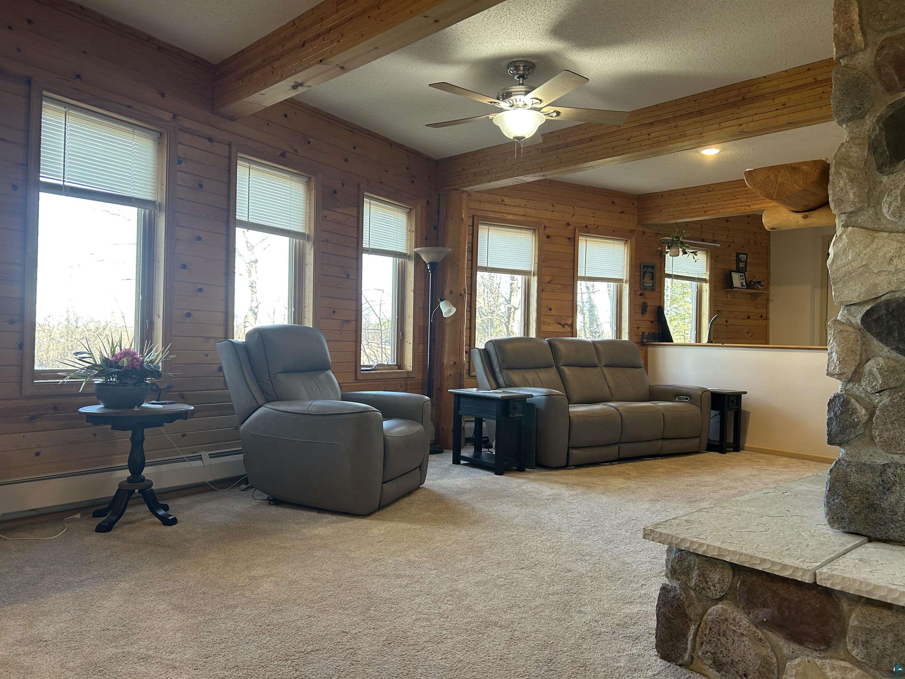 8655 South Lyman Lake Road South Range, WI 54874 - Photo 56 of 64 Living area with light colored carpet, beamed ceiling, a ceiling fan, wood walls, and a textured ceiling