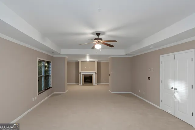 a view of an empty room with chandelier fan and fire place