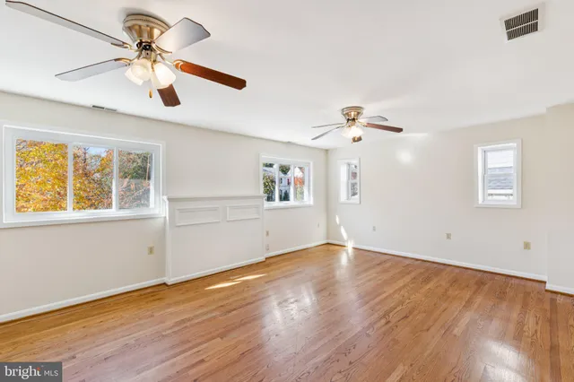 a view of an empty room with window and wooden floor