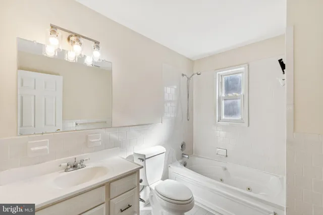 a bathroom with a bathtub shower sink vanity and toilet