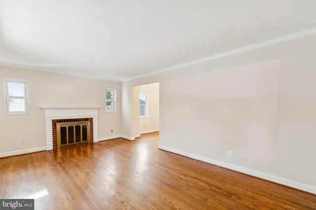 an empty room with wooden floor fireplace and windows