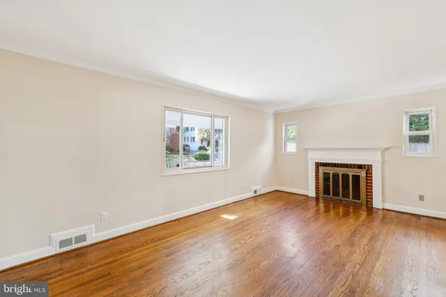 an empty room with wooden floor fireplace and windows