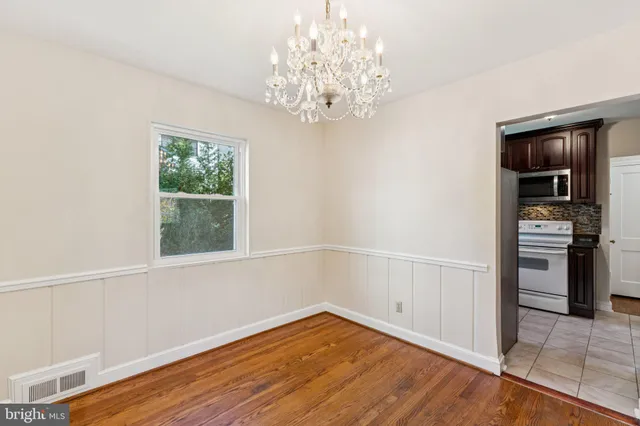 a view of empty room with wooden floor and kitchen