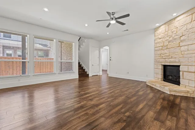 an empty room with wooden floor fireplace and windows