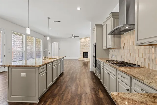 a large kitchen with stainless steel appliances granite countertop a lot of counter space and wooden floors