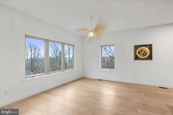 a view of an empty room with wooden floor and a kitchen