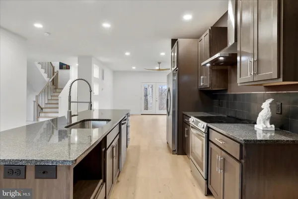 a kitchen with stainless steel appliances granite countertop a refrigerator a sink a stove and a wooden floors