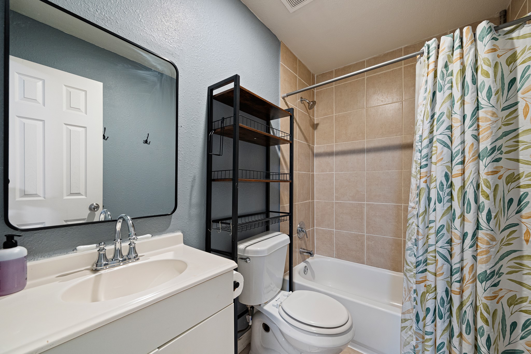 7815 Harding Street, Unit B Houston, TX 77012 - Photo 18 of 21 Discover a stylish full bathroom featuring modern fixtures, ample storage, and a vibrant shower curtain that adds a touch of elegance.