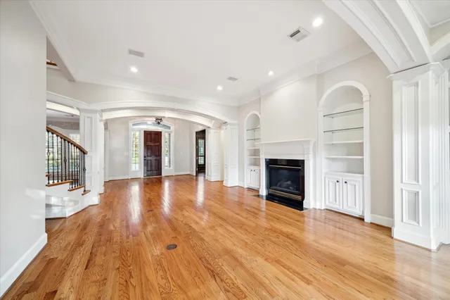 a view of an empty room with wooden floor fireplace and a window