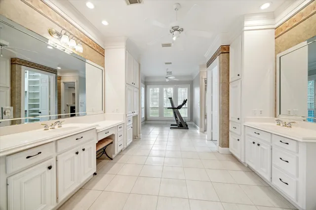 a large white bathroom with a granite countertop double vanity sink a mirror and a bathtub