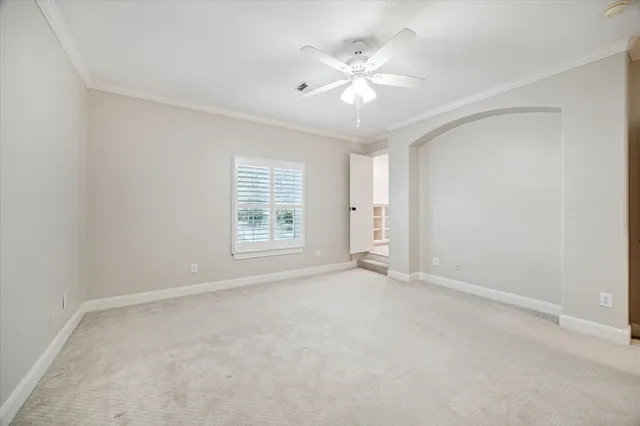 an empty room with windows and chandelier fan