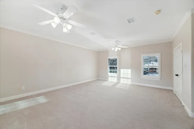 an empty room with windows and fan