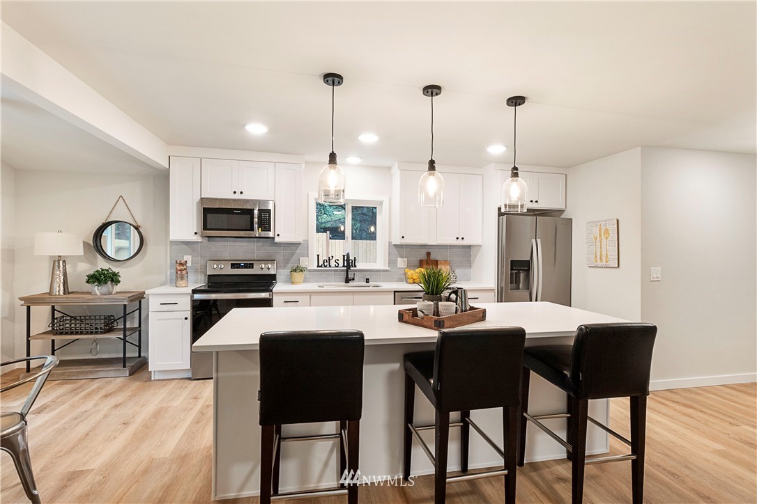 15 231st Street Southeast Bothell, WA 98021 - Photo 7 of 26 a kitchen with stainless steel appliances kitchen island granite countertop a dining table chairs and a refrigerator