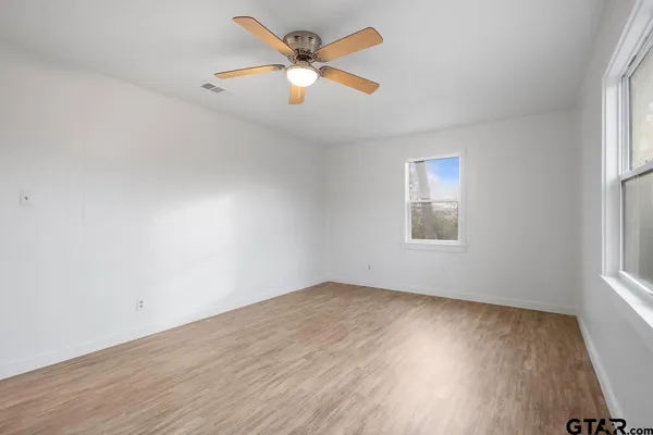 an empty room with wooden floor and windows