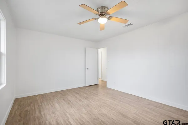 an empty room with wooden floor and fan